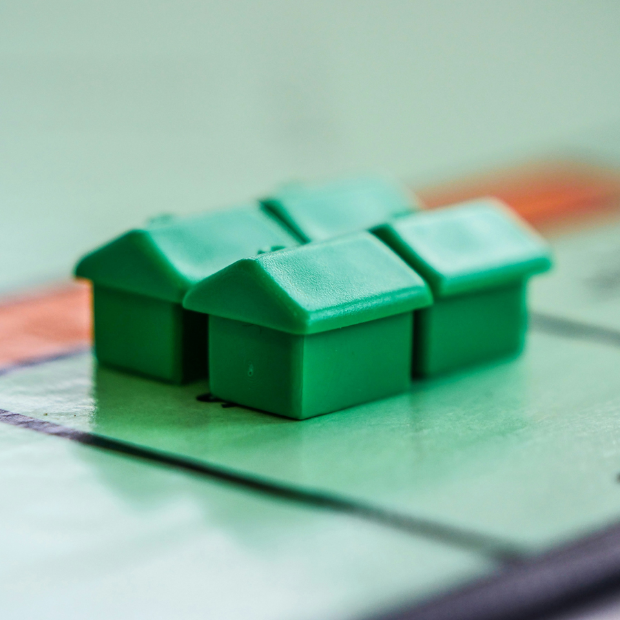 Four plastic board game houses on a board